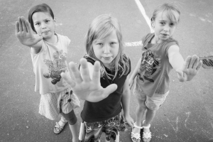 Drei Kinder stehen nebeneinander und strecken jeweils eine Hand mit offener Handfläche nach vorne